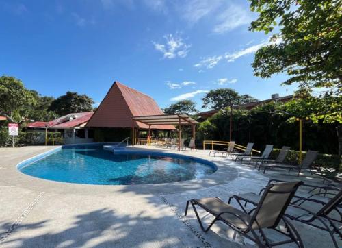 a swimming pool with chairs and a gazebo at Nacazcol - Playas del Coco in Coco
