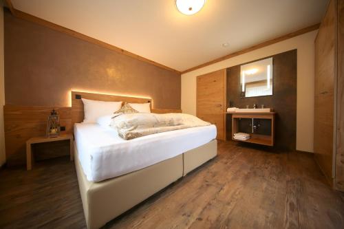 a bedroom with a large white bed with a wooden floor at Chalet Alpinhome in Tux