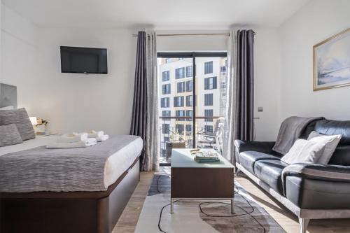 une chambre avec un lit, un canapé et une télévision dans l'établissement Forum Ocean View 4B by Homie, à Funchal