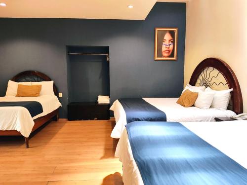 a hotel room with two beds and a picture on the wall at Hotel Jardines del Centro in San Cristóbal de Las Casas