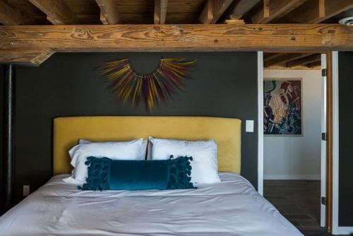 a bed with a yellow headboard and blue pillows at Barn of Three Oaks near Lake Michigan and Journeyman in Three Oaks