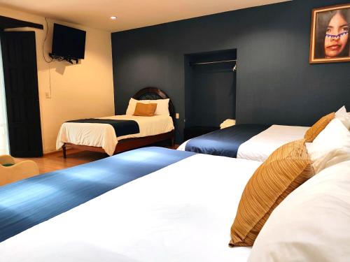a hotel room with two beds and a tv at Hotel Jardines del Centro in San Cristóbal de Las Casas