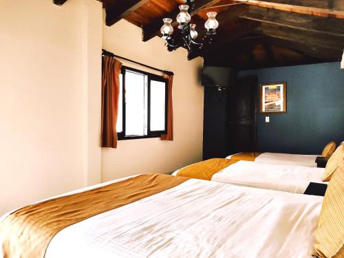 a bedroom with two beds and a window at Hotel Jardines del Centro in San Cristóbal de Las Casas