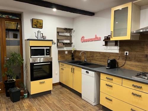 - une cuisine avec des placards jaunes et un évier dans l'établissement Voyage dans le temps, à Saint-Martin-du-Mont