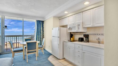 a kitchen with white cabinets and a table with a view at Oceanfront Studio in Daytona Beach Resort in Daytona Beach