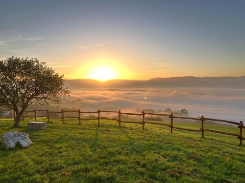 a fence in a field with a view of the sunset at Domaine des Étoiles - Logements Insolites in Gillonnay