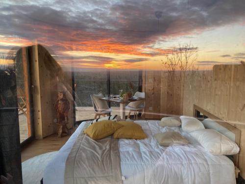 a bedroom with a large bed with a sunset painting on the wall at Domaine des Étoiles - Logements Insolites in Gillonnay