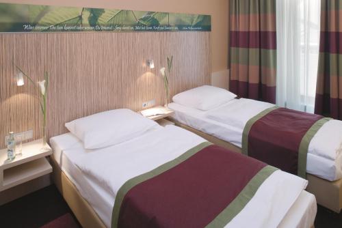 a hotel room with two beds in a room at Mövenpick Hotel Frankfurt City Messe in Frankfurt/Main