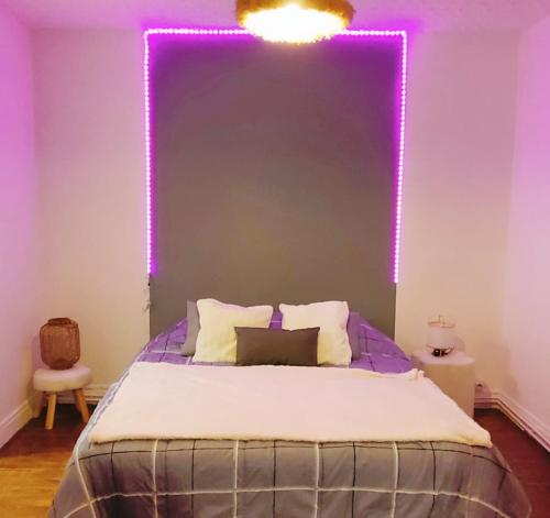 - une chambre dotée d'un lit avec des lumières violettes sur le mur dans l'établissement 150m plage COEUR DE BERCK, à Berck-sur-Mer