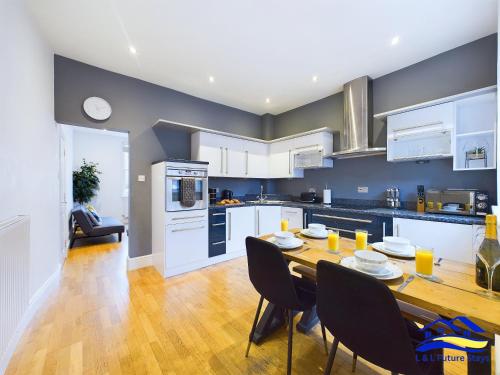 a kitchen and dining room with a wooden table and chairs at 2 Bed Ensuite, Secure Parking, Fast WiFi & SmartTV in Derby