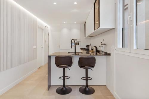 a kitchen with two bar stools at a counter at Golden Mile Lux Sea View Suite with Balcony in Marbella