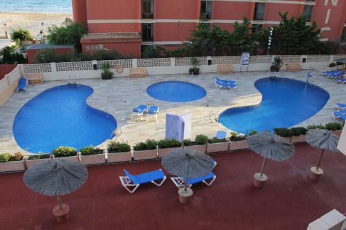 two pools with chairs and umbrellas in front of a building at Amatista 12 D - Private in Calpe
