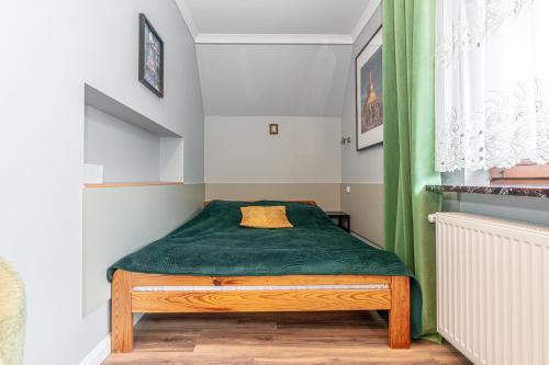 a small bedroom with a bed with a green blanket at Willa Jaś I Małgosia in Kościelisko