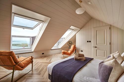 a attic bedroom with a bed and two chairs at Saltrock House - Portrush in Portrush