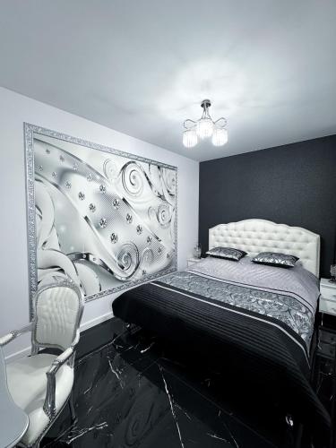 a black and white bedroom with a bed and a chair at Apartament Glamour in Gniezno