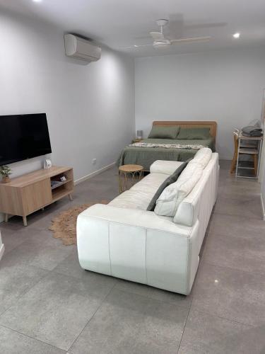 a living room with a white couch and a bed at Location, location, location - modern studio in Brisbane