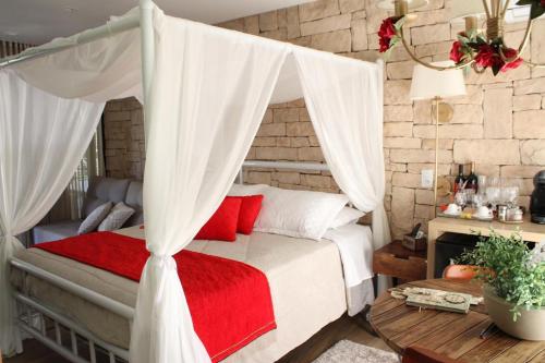 a bedroom with a canopy bed with red pillows at Pousada L'Amore in Siderópolis