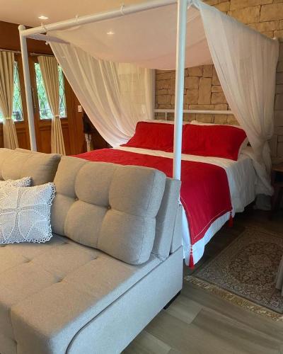a bedroom with a canopy bed with a couch at Pousada L'Amore in Siderópolis