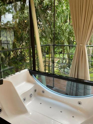 a bath tub in front of a large window at Pousada L'Amore in Siderópolis