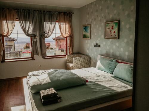 une chambre avec un lit, une chaise et des fenêtres dans l'établissement къща за гости villa Jurta, à Avren