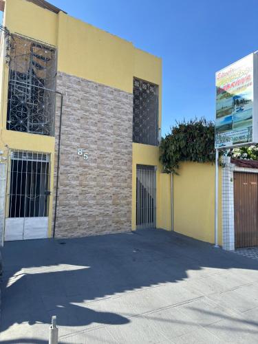 a yellow building with a gate and a garage at Pousada Extensão Sabrinna in Maceió
