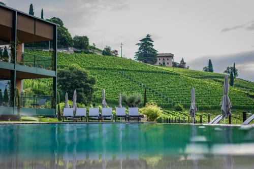 a pool with chairs and umbrellas next to a building at VILLA NAJ in Termeno
