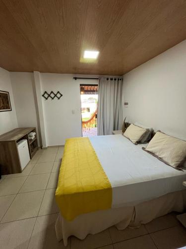 a bedroom with a large bed with a yellow blanket at Pousada Aconchego in Pitimbu