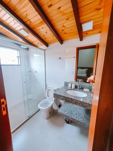 a bathroom with a toilet and a sink and a shower at Suítes da Penha in Capitólio