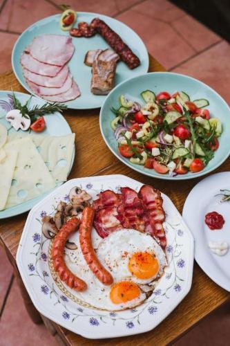 a table topped with plates of food with sausage and salad at Rózsakert in Romhány