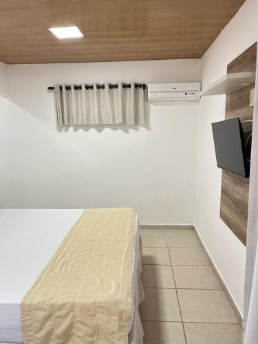 a bedroom with a bed and a tv on a wall at Pousada Aconchego in Pitimbu