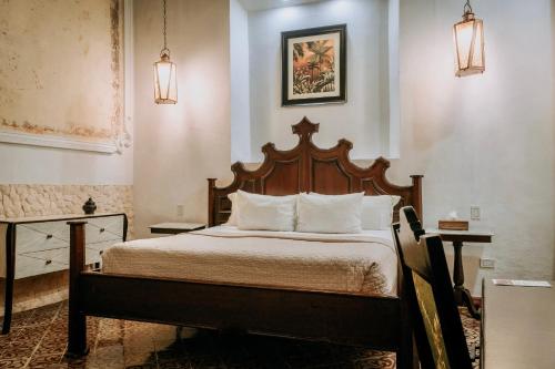 a bedroom with a wooden bed with white pillows at VILLA MERIDA BOUTIQUE HOTEL - Adults Only in Mérida