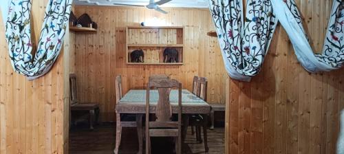 a dining room with a table and chairs and wooden walls at Magnolia Homestay in Srinagar