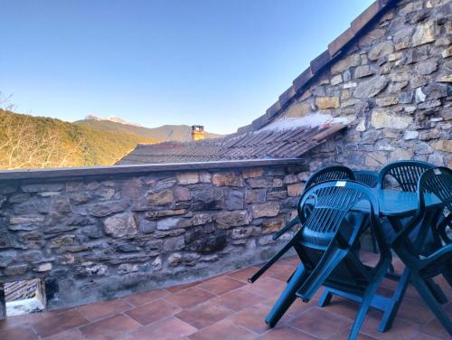a patio with two chairs and a table on a stone wall at Casa Juez in Ascaso