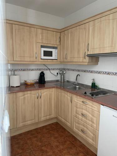 a kitchen with wooden cabinets and a sink and a microwave at La torrecilla in Zuheros
