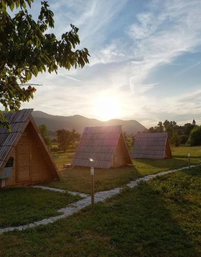 a group of barns with the sun in the background at Lika Sunset in Ličko Lešće