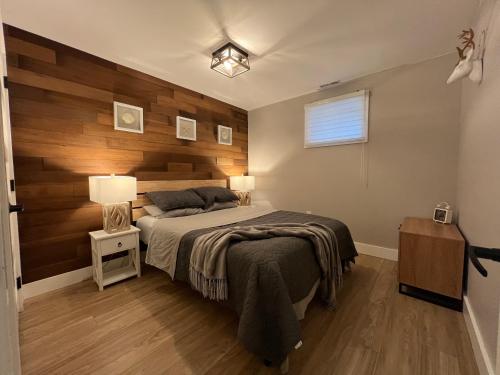 a bedroom with a bed with a wooden wall at The Luxe Lodge in Algonquin Highlands