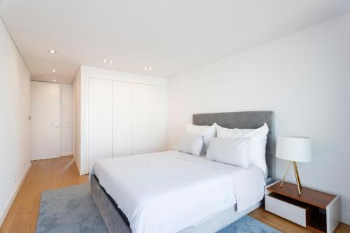 una camera bianca con un grande letto e una lampada di Luxury Suite With Balcony and Shared Accommodation in The Parque Eduardo VII Area a Lisbona