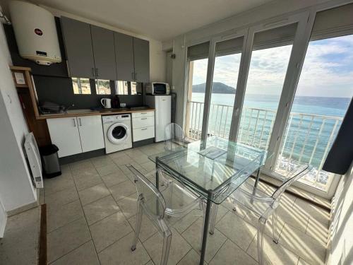 une cuisine avec une table et des chaises en verre et l'océan dans l'établissement Résidence Oustalet - Studio avec magnifique vue panoramique sur la mer à St Cyr Sur mer MAE-1611, aux Lecques