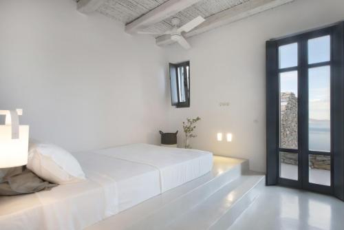 a white bedroom with a bed and a window at Houses G Y in Kardiani Tinos in Kardiani
