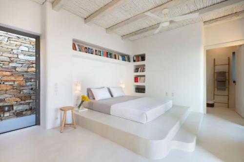 a white bedroom with a bed and a brick wall at Houses G Y in Kardiani Tinos in Kardiani