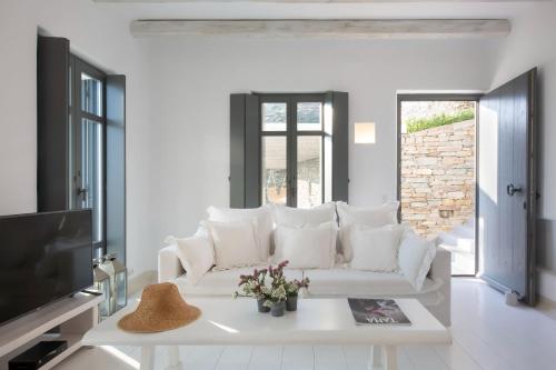 a living room with a white couch and a tv at Houses G Y in Kardiani Tinos in Kardiani
