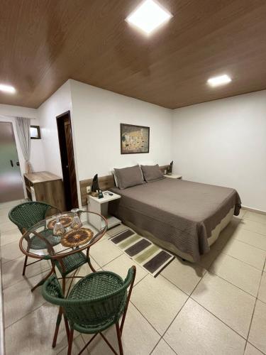 a bedroom with a bed and a table and chairs at Pousada Aconchego in Pitimbu