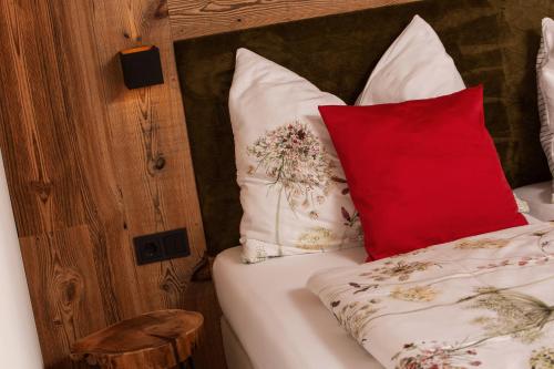 a bed with red and white pillows on it at Ella's in Fusch an der Glocknerstraße