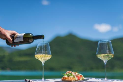 a person pouring white wine into two wine glasses at VILLA NAJ in Termeno