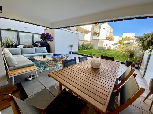 une terrasse ouverte avec une table et des chaises en bois dans l'établissement Cantosia - Appartement T3, Terrasse & Jardin Privatif, à Saint-Brès