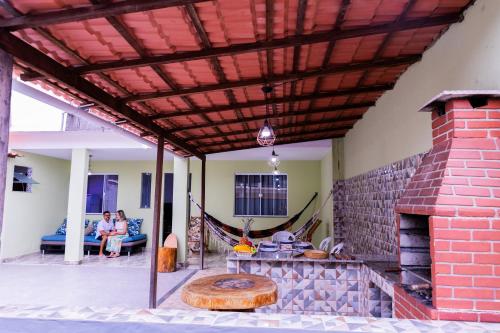 a patio with a brick fireplace and people sitting on a couch at Casa em Cabo frio, com quintal privado e área gourmet in Cabo Frio
