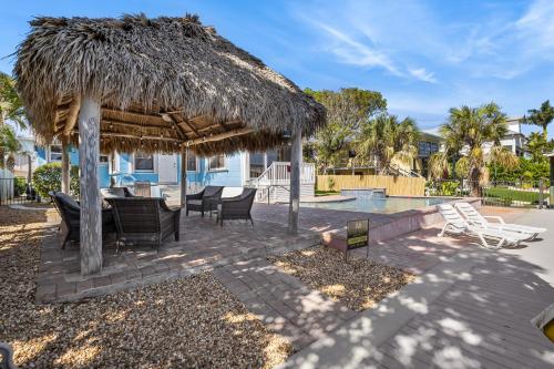 a patio with a straw umbrella and a table and chairs at Gulf Access, Heated Pool & Spa, Tiki Hut - Roelens in Fort Myers Beach