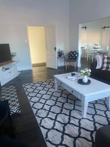een woonkamer met een witte salontafel en een bank bij Daisy Cottage, 4 bedrooms, close to CBD in Golden Square