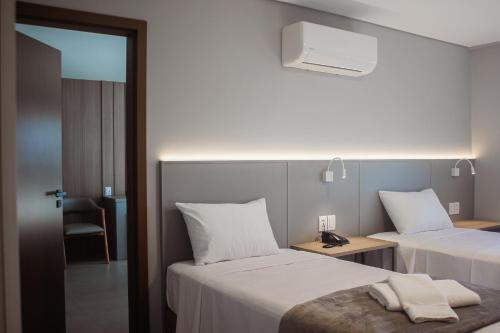 a hotel room with two beds and a chair at Hotel San Marinho in União da Vitória
