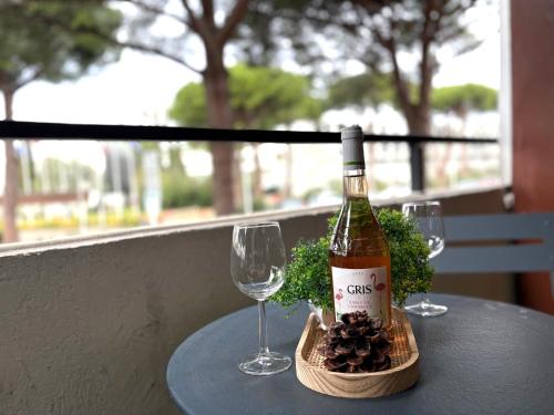 une bouteille de vin posée sur une table avec deux verres dans l'établissement L'AMAZONE studio plein centre PLAGES à 2min CLIM WIFI sur le port - Top ProsConciergerie-, à La Grande Motte